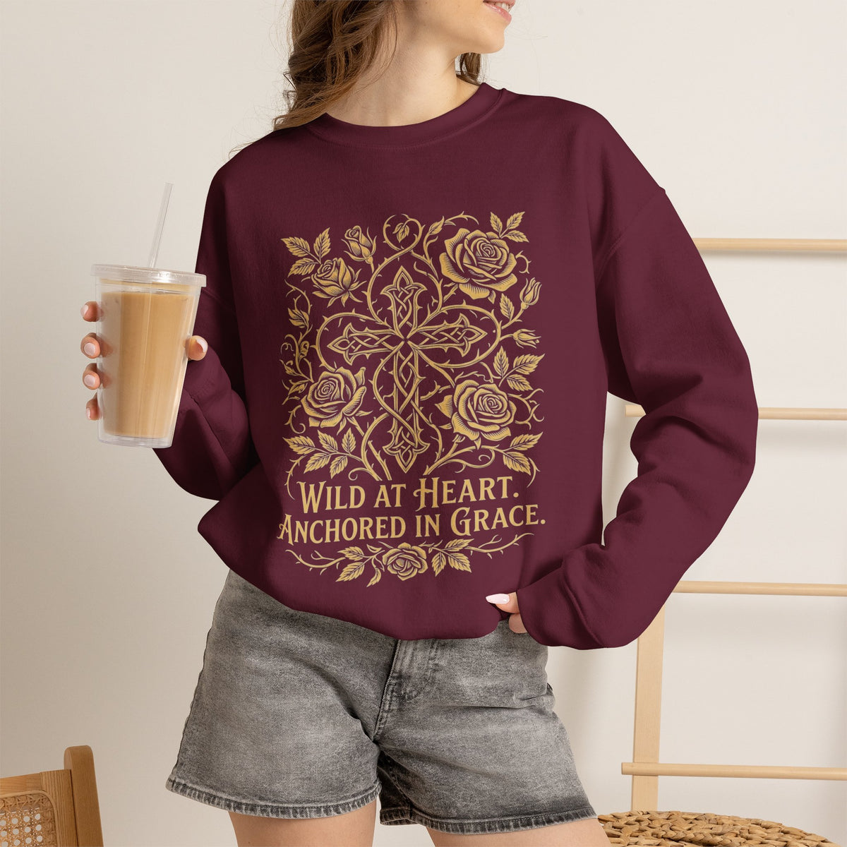 Wild at Heart Anchored in Grace faith floral crewneck sweatshirt in maroon with gold floral cross design, worn by woman