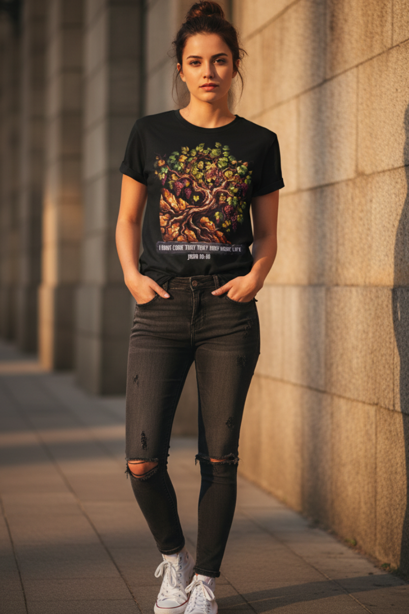 Young woman wearing black John 10:10 grapevine Christian t-shirt, hands in pockets, leaning against stone wall in golden hour sunlight, dark jeans and white sneakers, urban editorial style